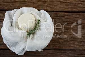 Cottage cheese and rosemary herb in white cloth on wooden board