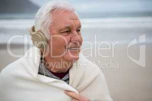 Senior man wearing shawl and listening music on headphones