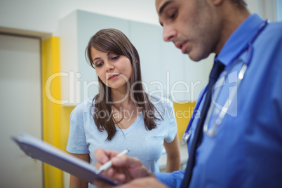 Doctor interacting with patient and writing on clipboard