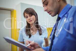 Doctor interacting with patient and writing on clipboard