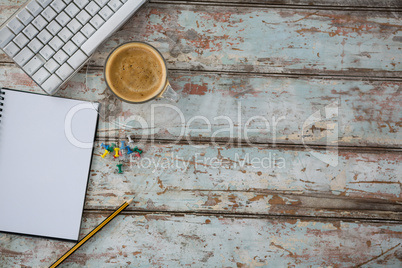 Coffee, pushpin, pencil, computer keyboard and organiser on wooden table