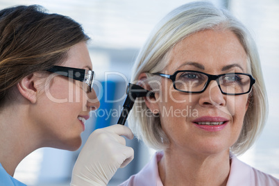 Doctor examining patients ear with otoscope