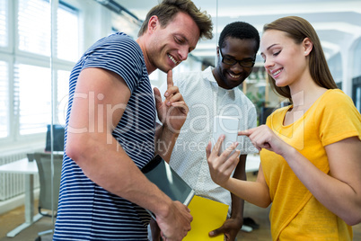 Graphic designer showing something on mobile phone to colleagues