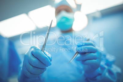 Surgeon holding surgical tools in operation theater