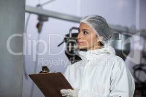 Female butcher maintaining records on clipboard