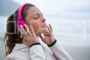 Beautiful woman listening music on headphones at beach