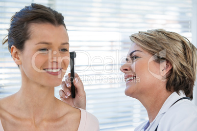 Doctor examining patients ear with otoscope