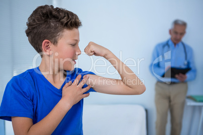 Portrait of boy flexing his biceps in the clinic