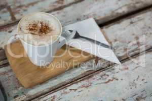 Cup of coffee and spoon on wooden tray
