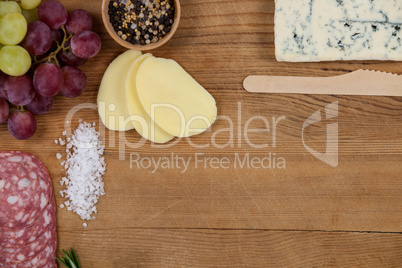 Roquefort cheese, grapes and ham with various ingredients on chopping board
