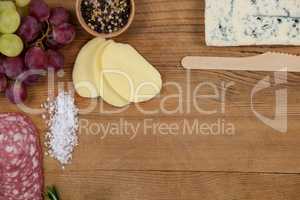 Roquefort cheese, grapes and ham with various ingredients on chopping board