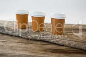 Disposable coffee cups on wooden plank