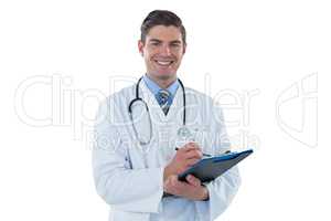 Smiling doctor writing with pen on clipboard