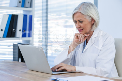 Thoughtful female doctor working on her laptop