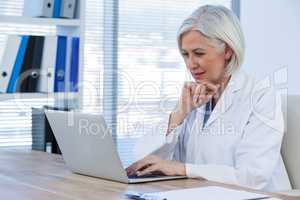 Thoughtful female doctor working on her laptop