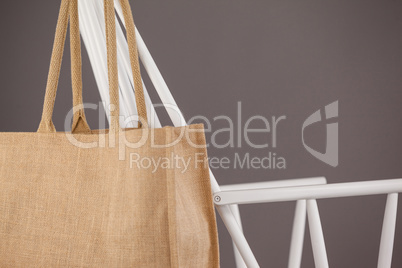 Beige fabric bag hanging on a white chair