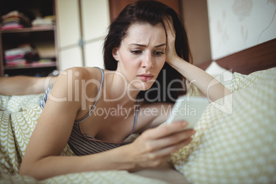 Woman using mobile phone while man sleeping on bed