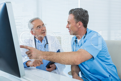 Surgeon and doctor discussing over personal computer