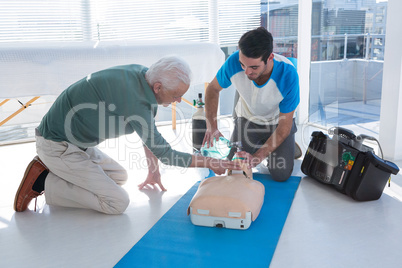 Paramedics practicing cardiopulmonary resuscitation on mannequin