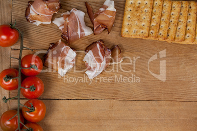 Pieces of meat with cherry tomatoes and biscuits on chopping board