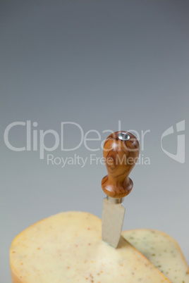 Knife on cheese slices on wooden board