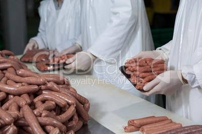 Butchers packing raw sausages