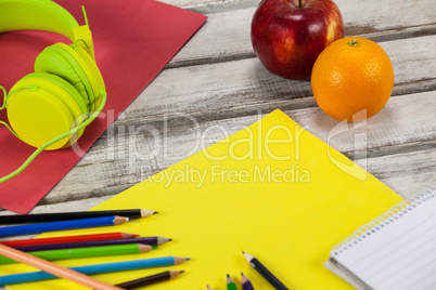 Color pencils, notepad, placard, fruits and headphones