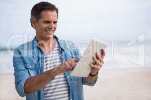 Man using digital tablet on beach