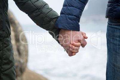 Close-up of couple holding hands on the beach