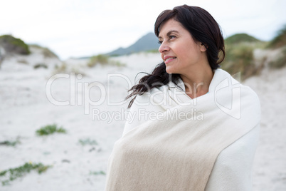 Thoughtful woman wrapped in shawl on beach