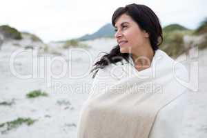 Thoughtful woman wrapped in shawl on beach