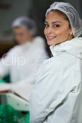 Smiling butcher standing in meat factory