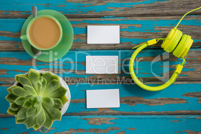 Coffee with headphones, sticky notes and pot plant on table