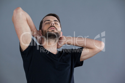 Man in black t-shirt with hands behind his neck