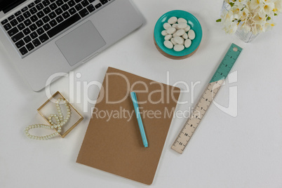 Laptop, pearl necklace, ruler, pen, diary and pebbles