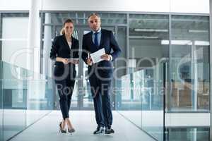 Portrait of business colleagues standing with digital tablet in corridor