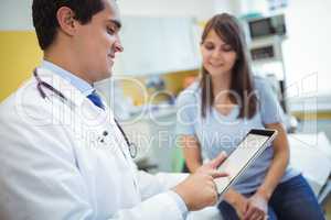Doctor using digital tablet while consulting patient
