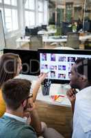 Graphic designers discussing over computer at their desk