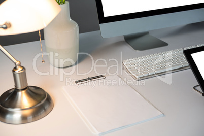 Desktop pc, and table lamp with blank paper sheets