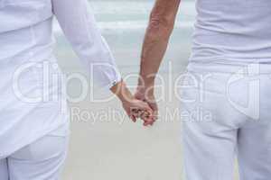 Mid section of couple holding hands on beach