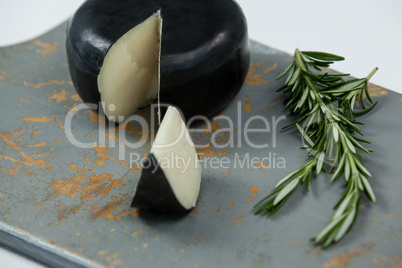 Black cheese with rosemary on chopping board