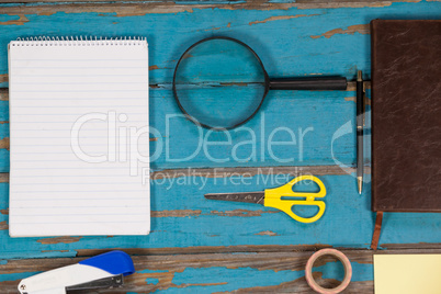 Notepad, magnifying glass, scissor, stapler, pen sellotape and diary