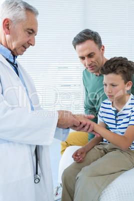 Father looking at sons hand while being examined by doctor