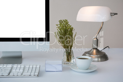 Desktop pc with coffee and table lamp on table
