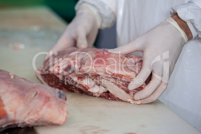 Butcher holding raw meat at meat factory