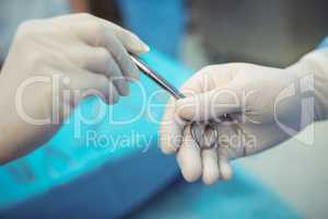 Surgeon passing surgical scissors to colleague in operation theater
