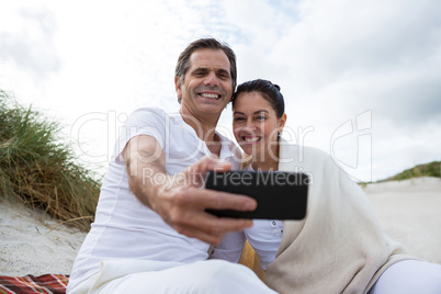 Happy couple taking selfie on beach