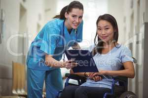 Portrait of female nurse assisting patient over clipboard