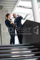 Business colleagues standing on a staircase and talking to each other