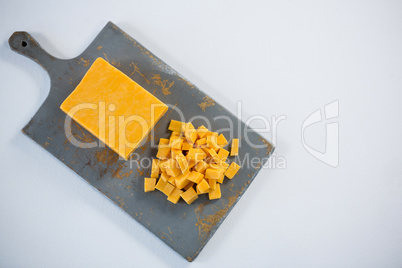 Block and cubes of cheese on chopping board